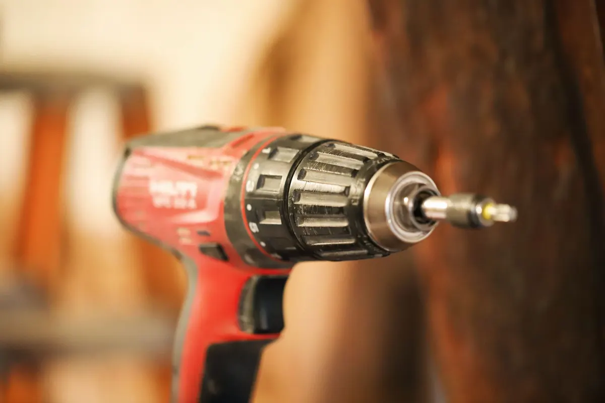 Cordless impact driver driving screws into deck lumber on a construction site